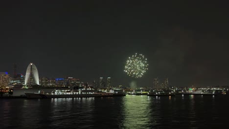 bright fireworks illuminate the skyline during the yokohama port festival, with vibrant lights reflecting off the water