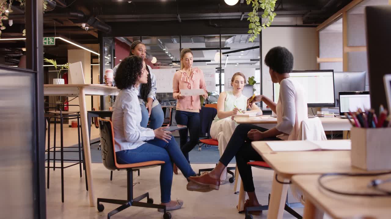 Diverse female business creatives discussing project at work, in slow motion