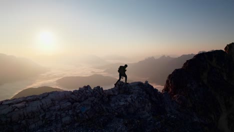un montañero camina por una cresta y mira hacia el amanecer