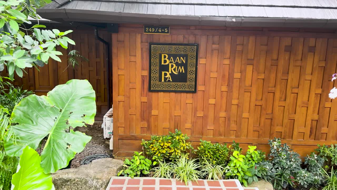 una vista serena del exuberante jardín tropical de baan rim pa, que muestra una vegetación vibrante y la arquitectura tradicional de teca en phuket, tailandia