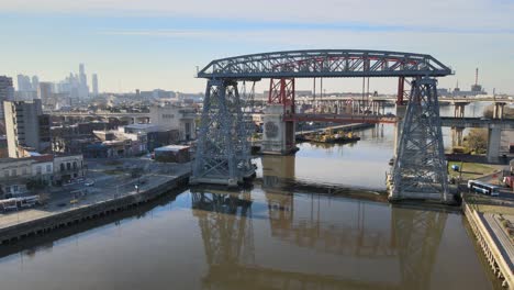 Drone-hovering-above-Matanza-river-on-a-sunny-day-facing-the-famous-historical-monument-bridge-Puente-Transbordador-Nicolas-Avellaneda-and-downtown-cityscape