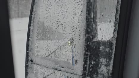 the rearview mirror of the car is covered with wet snow during the storm