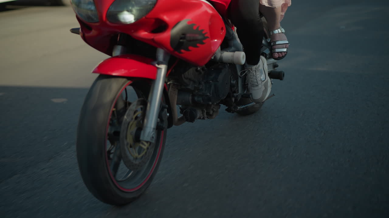 vista de las piernas de dos damas montando una bicicleta eléctrica en una carretera urbana, con sus sombras proyectadas en el suelo