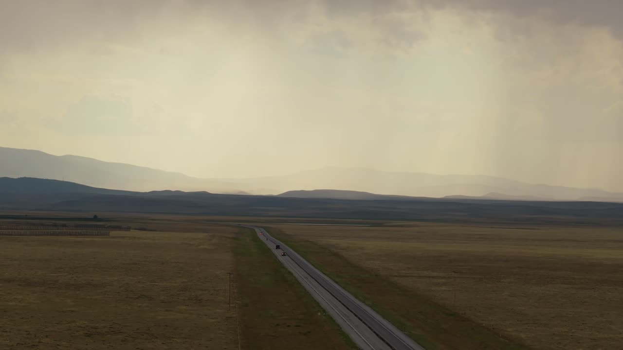 Empty road through vast, serene Wyoming landscape under cloudy skies