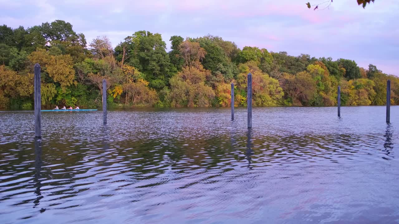 широкий снимок людей, гребущих на реке на закате солнца
