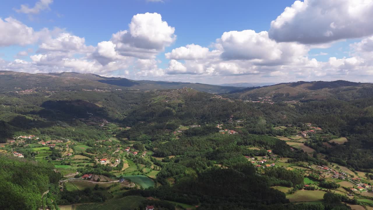 Paesaggio aereo delle valli lussureggianti e delle dolci colline del Minho sotto un cielo nuvoloso.