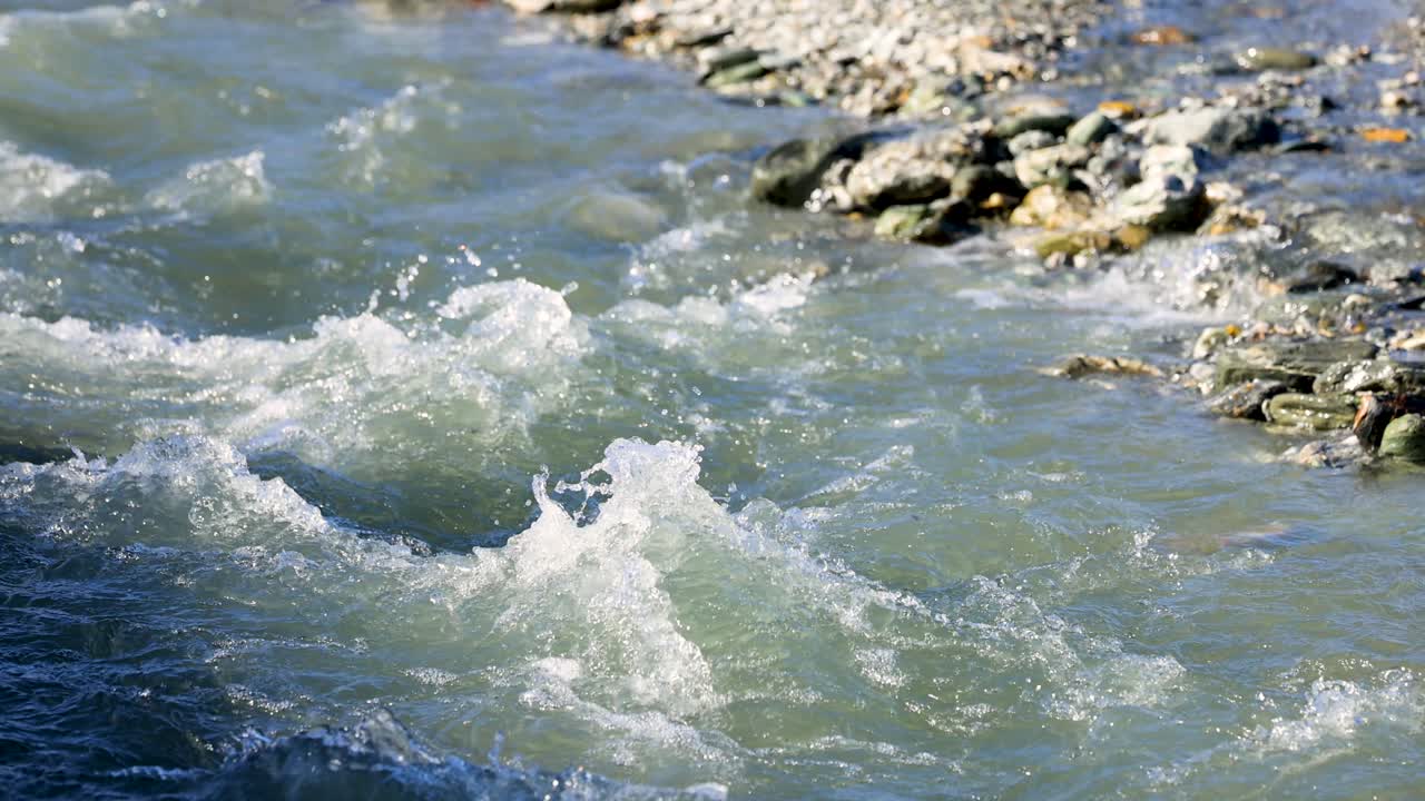 A fast-flowing stream with clear water over rocks, captured in bright daylight