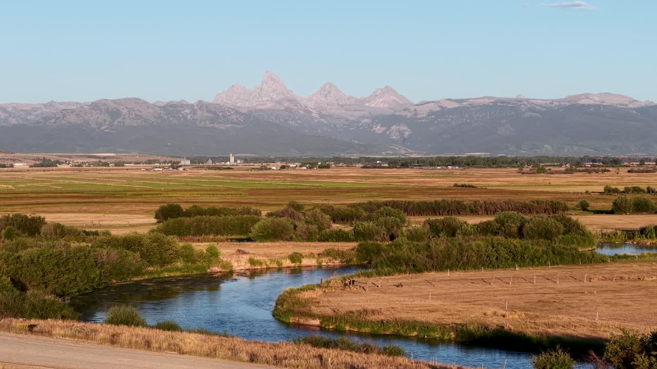 Ripresa aerea delle Grand Teton Mountains lungo la riva del fiume all'ora d'oro