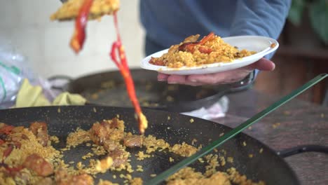 serving paella to a gathering of people celebrating