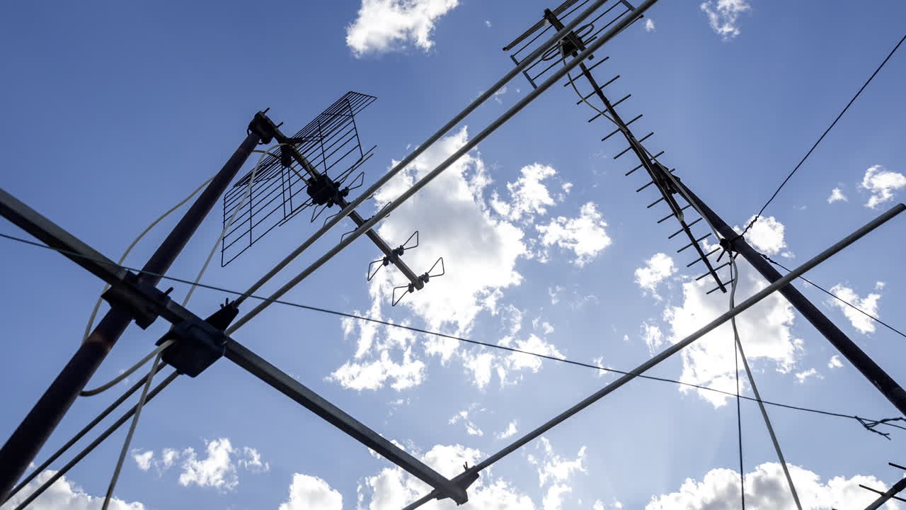 A timelapse of the sky and clouds with television aerials in the foreground
