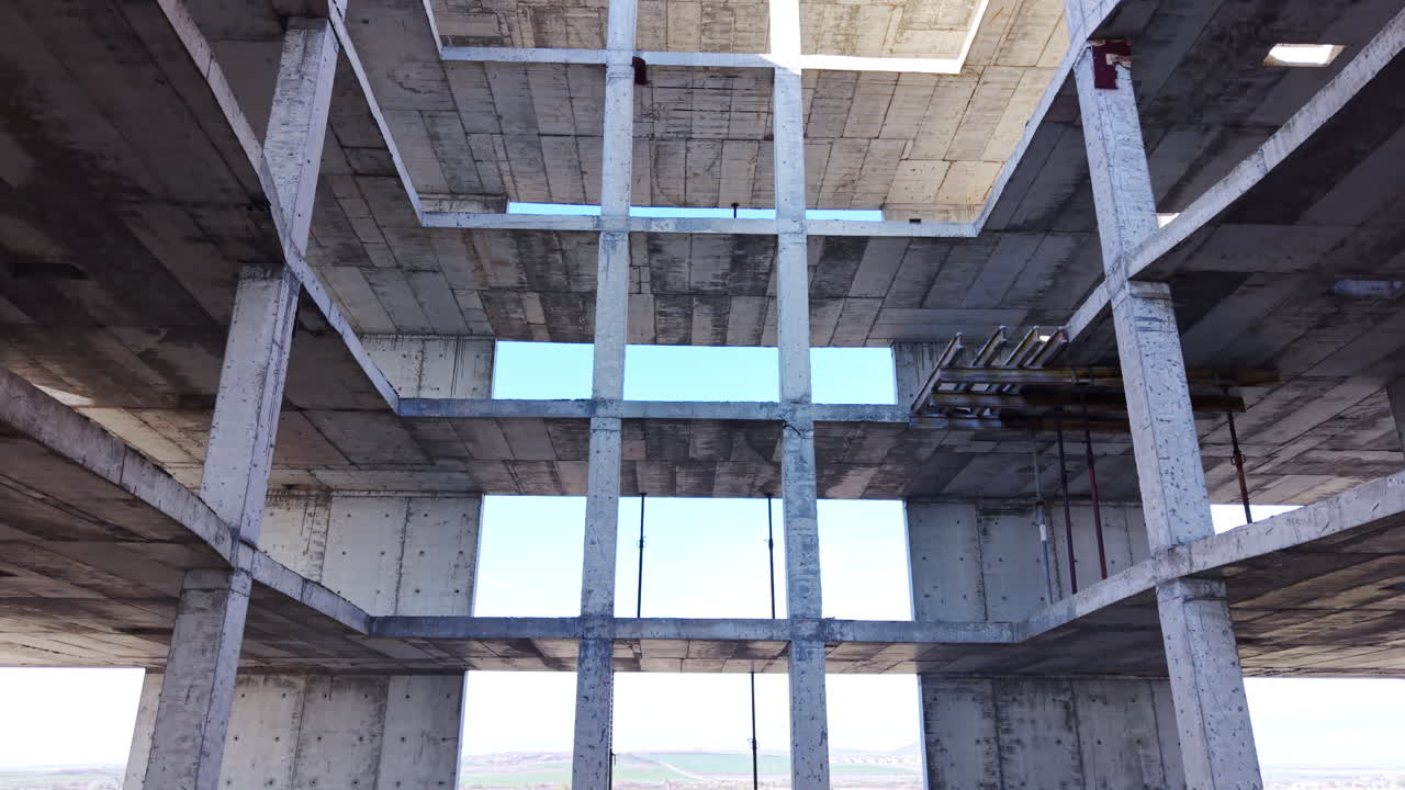 Low angle view of internal rectangular opening within multi story reinforced concrete structure. Looking up through central void of concrete building frame. Aerial