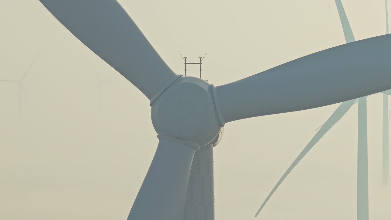 Close up of wind turbine blades rotating in foggy weather