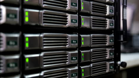 close-up of 4tb hard drives in a server rack, green lights indicate active status