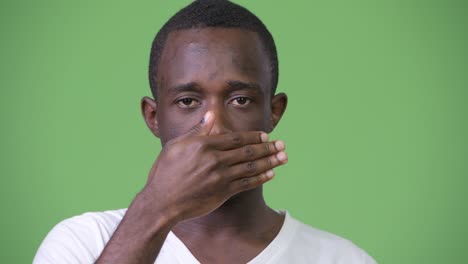 joven africano cubriendo los ojos como tres monos sabios concepto