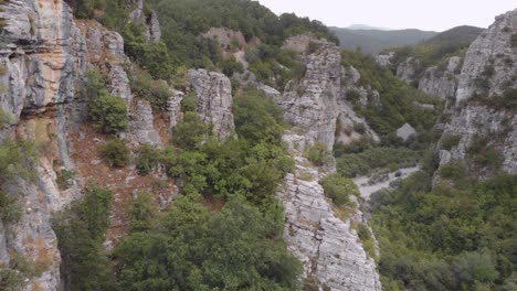 drone video flying through near steep rocks on a wild forest at zagori region greece on a cloudy day