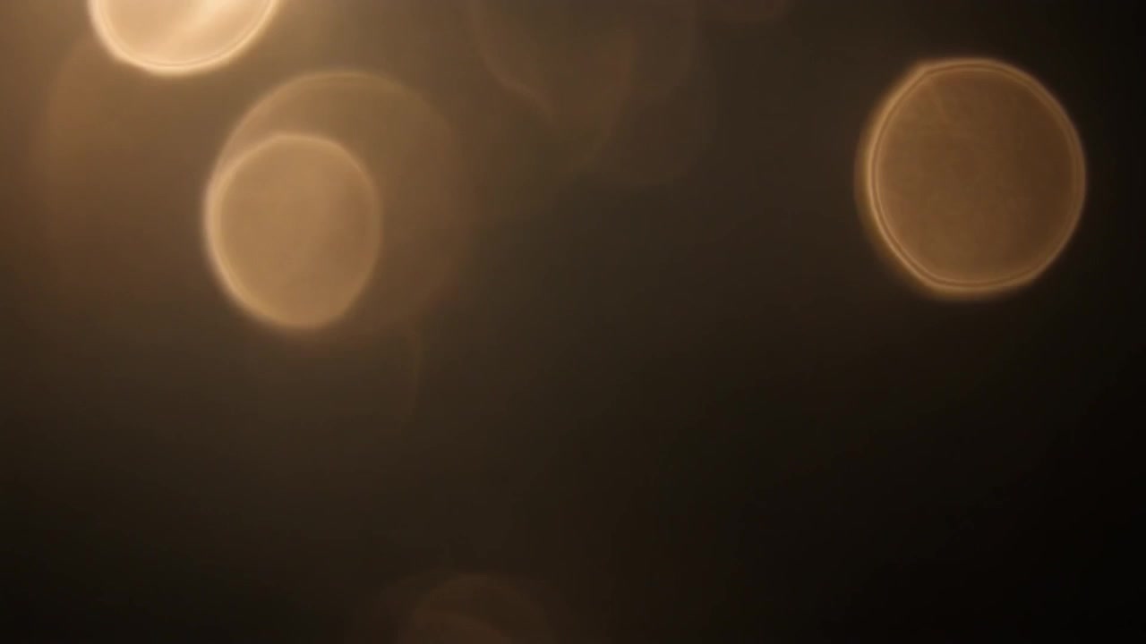 Abstract Golden Bokeh Light Particles Floating on Dark Background