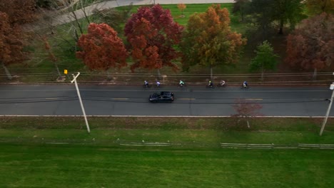 an aerial view over a quiet country field with a two lane country road and colorful trees on a sunny day in autumn