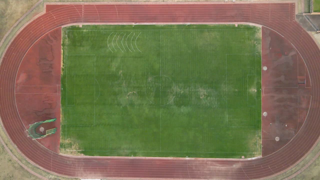 una antena acercándose lentamente a una pista y campo o campo de atletismo con un exterior polvoriento