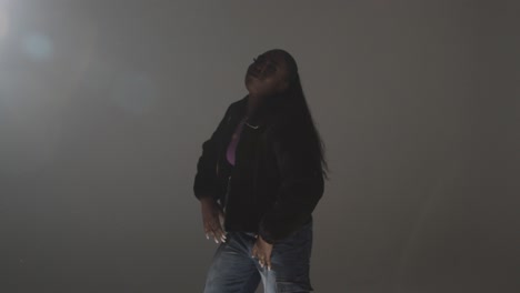 studio portrait shot of young woman dancing with low key lighting against grey background 13