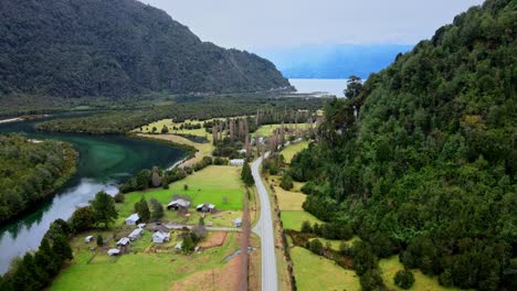 Dolly-out-aerial-view-of-the-entrance-to-Cochamo-with-the-Cochamo-River-on-the-side,-cloudy-mountains,-southern-Chile