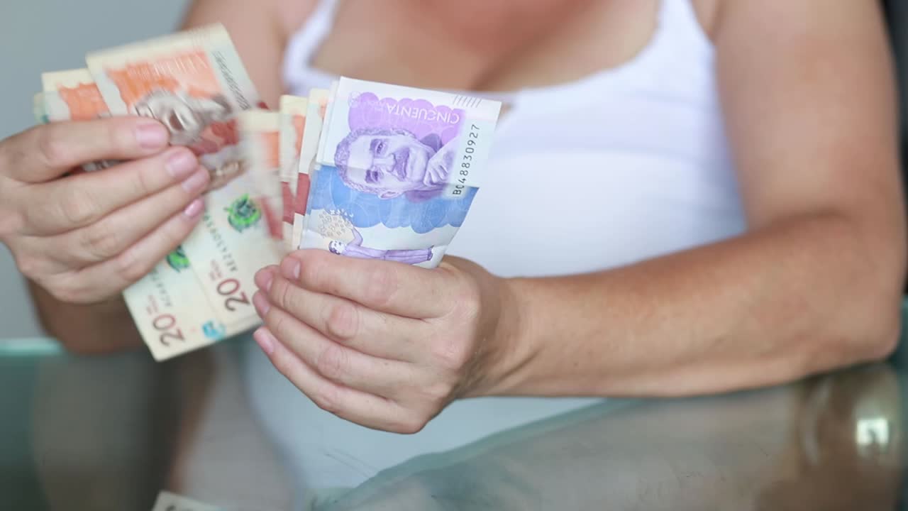 cerca de mujer mano contando dinero billetes en moneda colombiana