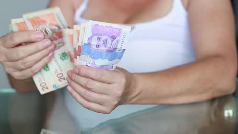 close up on woman hand counting money colombian currency bills