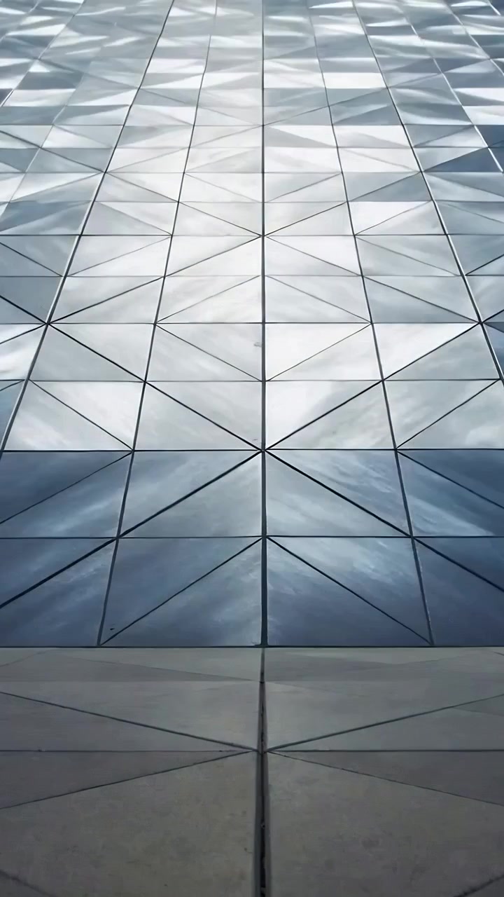Vertical video: Panning camera upward from concrete base showing diamond metal panels forming grid