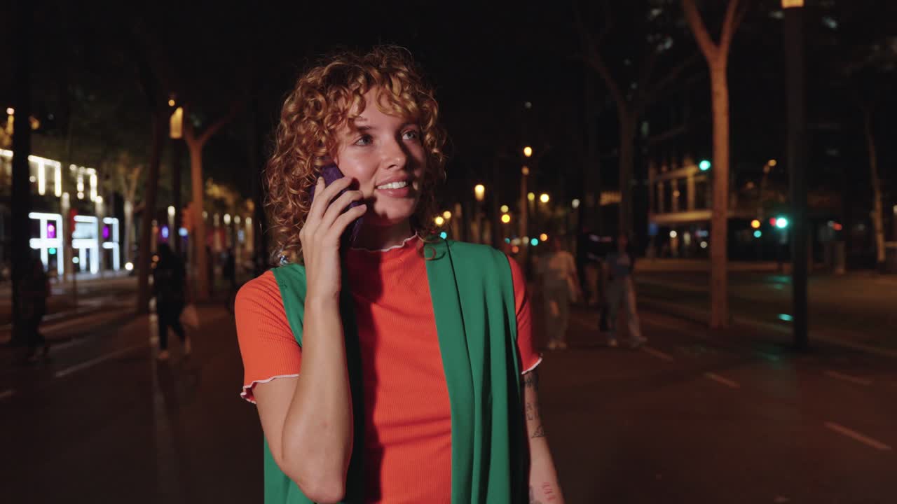 Donna che parla al telefono di notte in un ambiente urbano