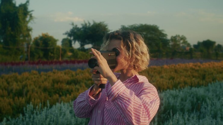 Young Woman Filming with Vintage Super 8 Camera in Flower Field