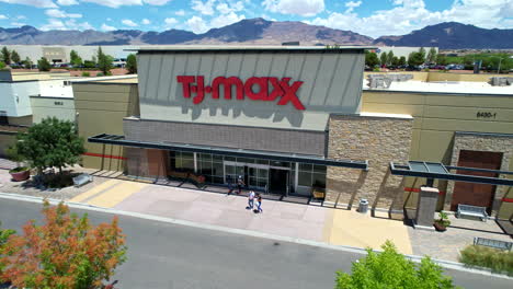 tj maxx. aerial drone view of popular american discount department store retail chain location storefront with customers walking in and out of store.