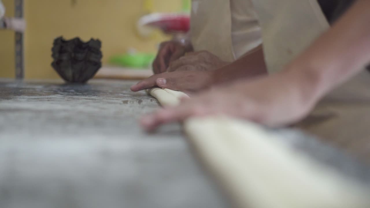 Pastry chef shaping dough on the countertop, preparing it for baking in the kitchen