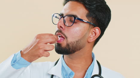 Indischer-Arzt,-Mann-Steckt-Weiße-Kapsel,-Tablette,-Pille-In-Den-Mund,-Empfiehlt-Medikamente,-Vitamin-Impfung