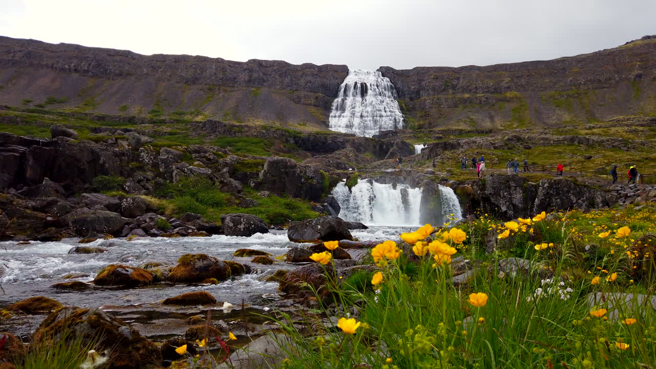 enorme cascada de dyjandi en los fiordos del oeste de islandia prorezhq de 4k estático ancho y bajo con turistas caminando a las cataratas en la distancia