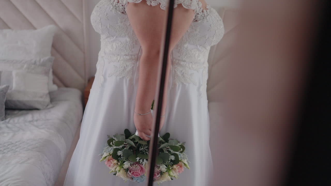 화려한 웨딩 드레스를 선보이는 거울에 반사된 꽃받침을 들고 있는 신부