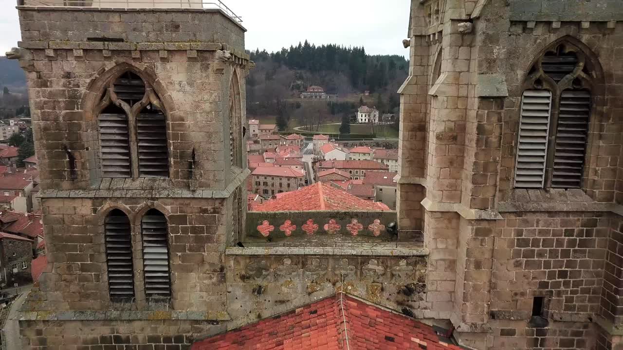 fotografía de un avión no tripulado que revela la iglesia colegiada de saint bonnet le chateau y el pueblo de monts du forez en un día nublado, departamento del loira, francia