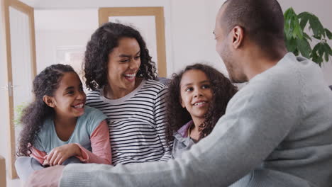 Familia-Tomando-Un-Descanso-Y-Sentándose-En-El-Sofá-Celebrando-Mudarse-Juntos-A-Un-Nuevo-Hogar