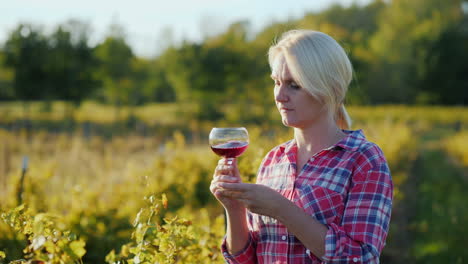 woman smelling red wine in vineyard