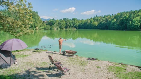 Fisher-standing-on-the-edge-of-a-small-lake,-fishing-with-multiple-rods-for-Carp