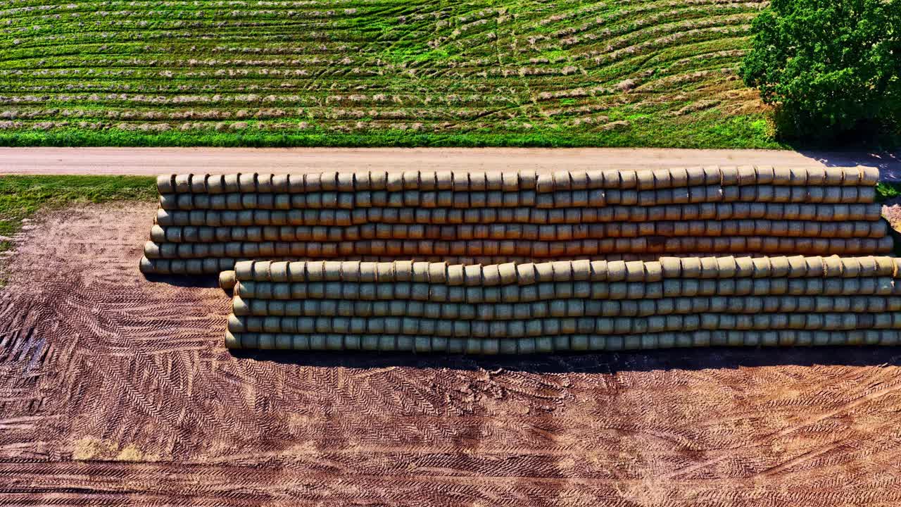 Aerial: pan drone shot of stack of stacked hays in a field during the day, outdoor