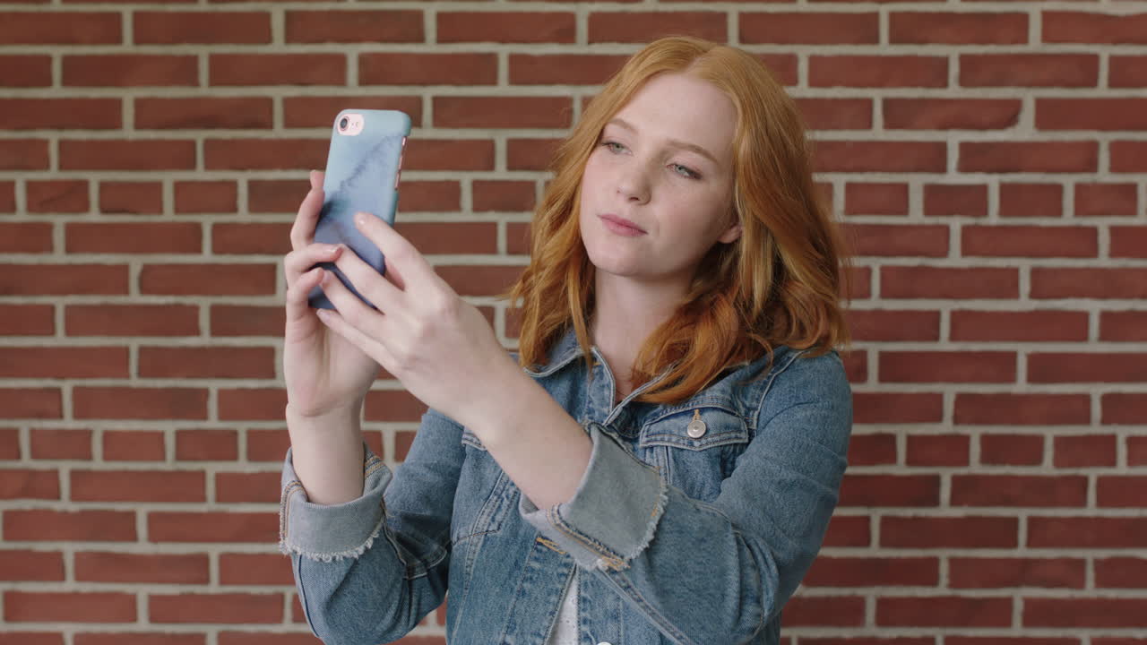 retrato de una hermosa mujer de cabello rojo usando un teléfono inteligente posando para una foto selfie