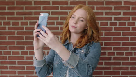 portrait of beautiful red head woman using smartphone posing for selfie photo