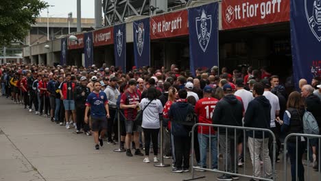 large crowd of fans waiting in line outside sporting venue for event entrance, showcasing excitement and anticipation among attendees