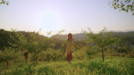 woman running in a yellow dress through an apple orchard at sunset