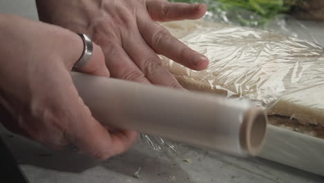 smorgastarta, scandinavian sandwich cake, is covered with plastic wrap