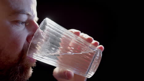 SLOW-MOTION-BACKLIT---Closeup-of-a-man-drinking-delicious-fresh-water-from-a-glass