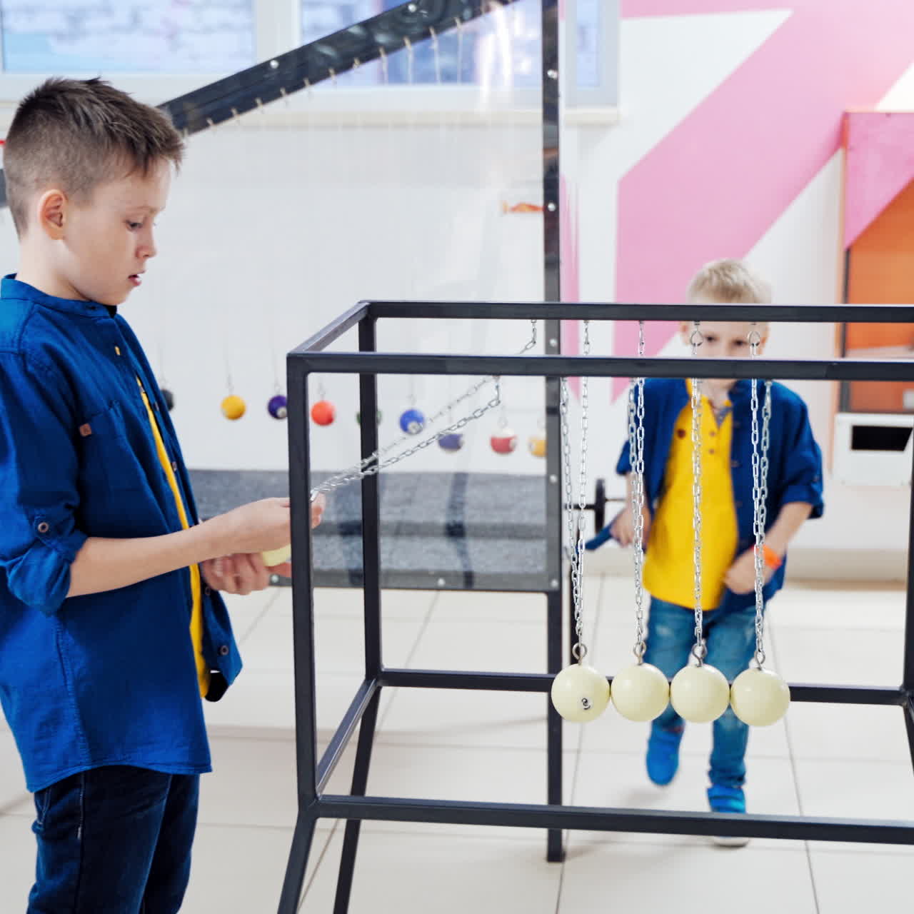 Newton's cradle. Action and reaction concept. Series of swinging spheres. Kids are playing.