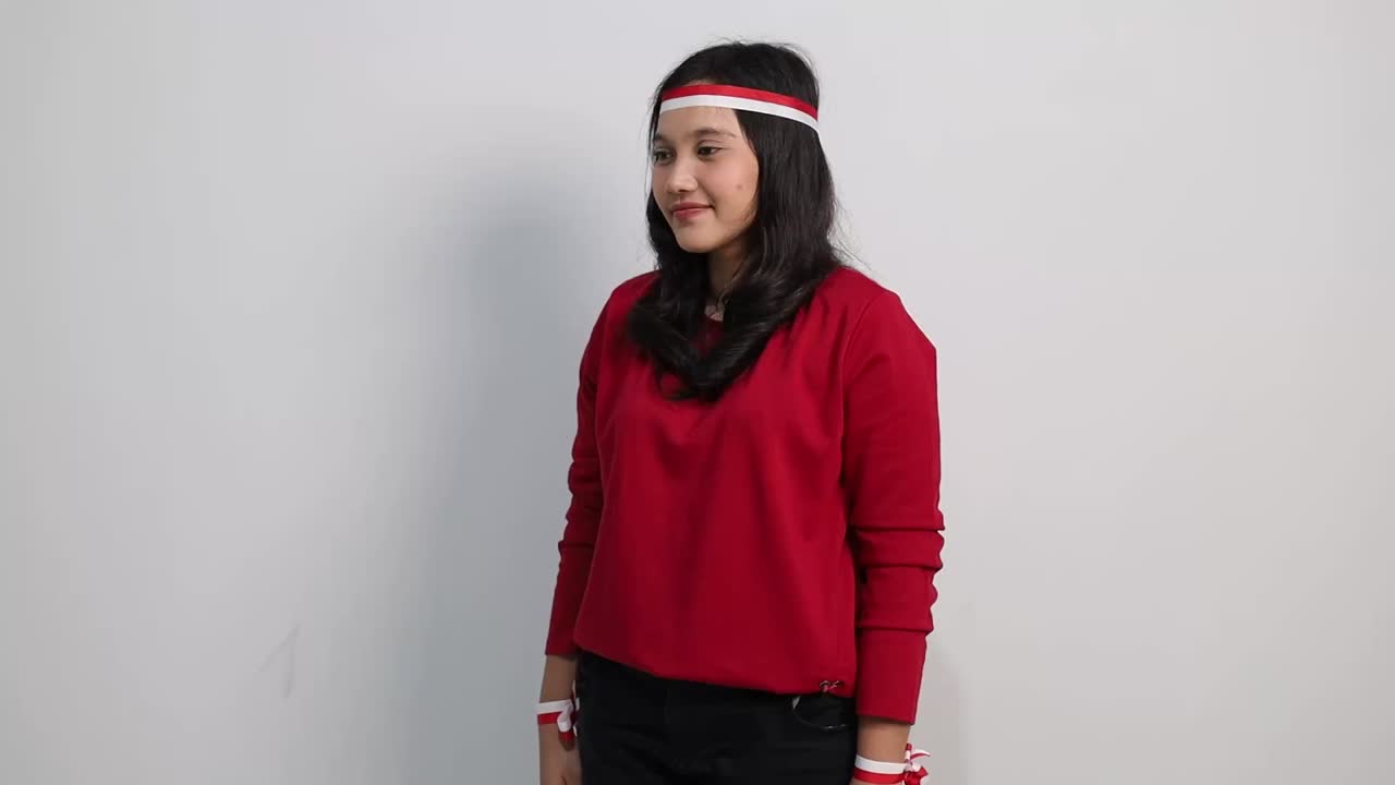 Asian woman giving salute to sideways and to the camera, celebrate Indonesian independence day on 17 August isolated over white background