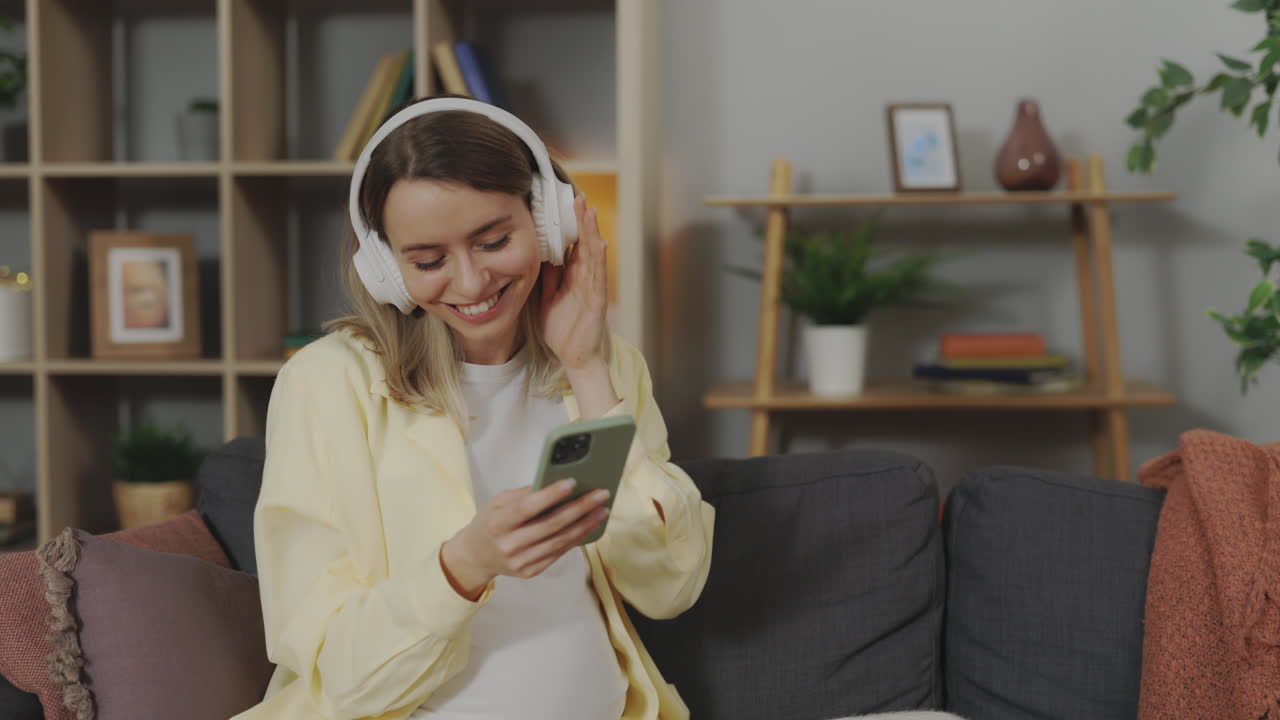 Donna incinta che si gode musica e videochiamate a casa