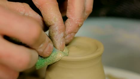 professional potter shaping mug with special tool in pottery workshop