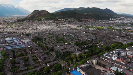 lijiang old town buildings extend toward the horizon with distant hills under blue sky, panoramic aerial establishing overview